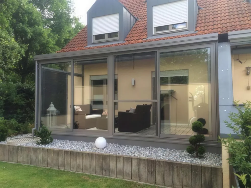 Grauer Glasanbau an einem Wohnhaus